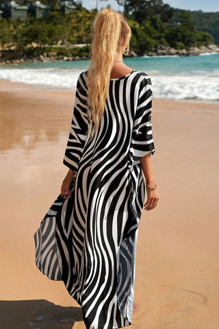 A woman wearing a V-neck print kaftan dress at the beach.