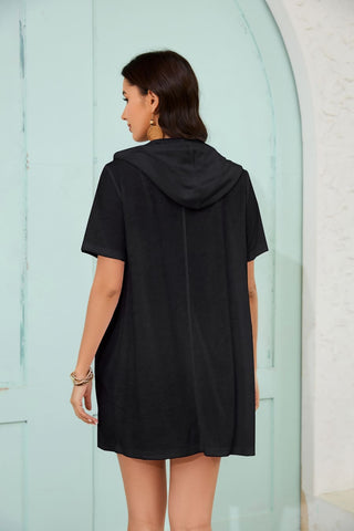 A woman wearing a black zipper hooded swimsuit coverup with pockets.