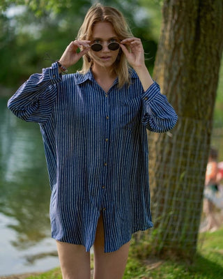 A woman wearing a button down sexy shirt cover up by the lake.