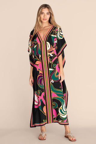 A woman wearing a geometric pattern maxi kaftan dress with smile.