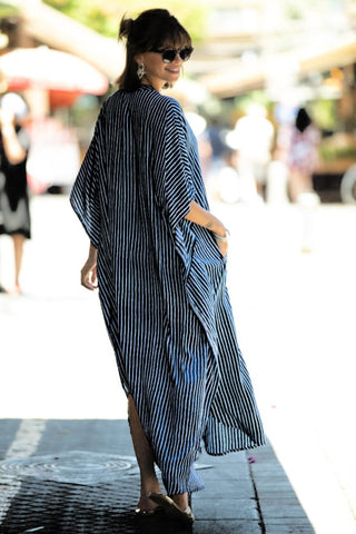 A woman wearing a maxi black V-neck caftan dress with sun-glasses.