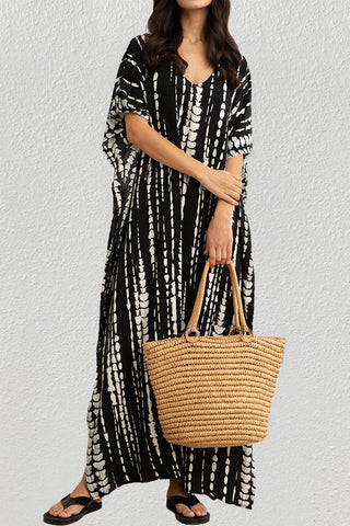 A woman wearing a black nice beach caftan cover up with a bag.